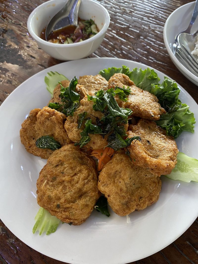 ทอดมันปลาโรยใบกะเพรากรอบ วางบนผักกาด