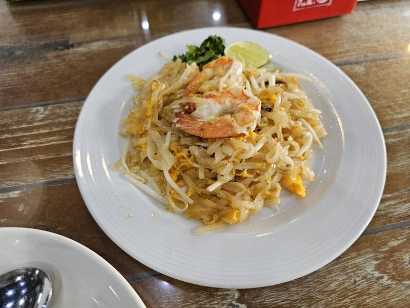 ผัดไทยใส่กุ้งตัวโตบนจานขาว